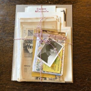 Ett paket med vintage pappersmaterial och gamla fotografier ihopbundet med ett rött och vitt snöre.