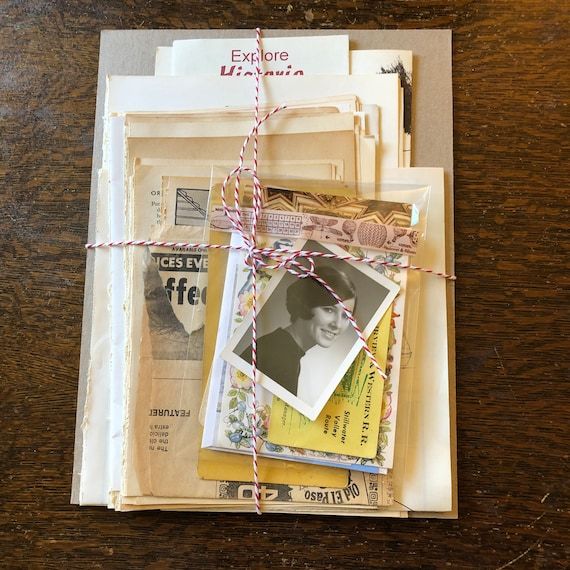 Ett paket med vintage pappersmaterial och gamla fotografier ihopbundet med ett rött och vitt snöre.