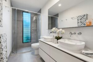 Modernt badrum med dusch bakom glas och dubbla handfat